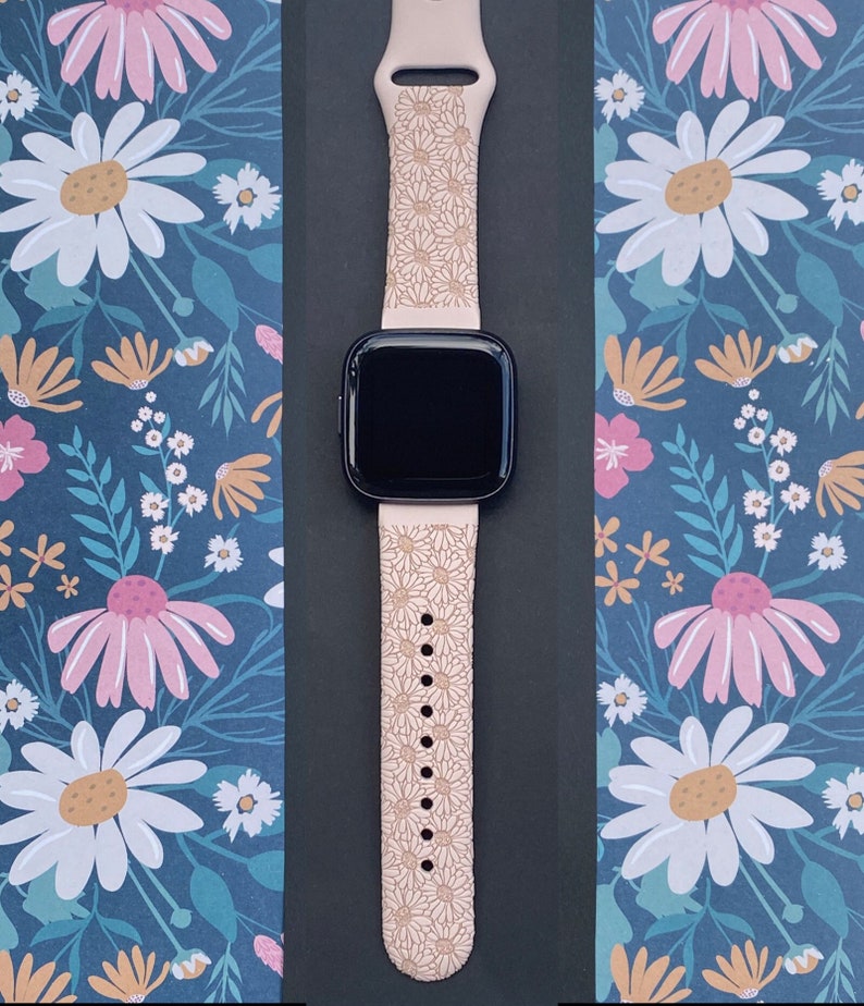 May include: A pink silicone watch band with a daisy print design. The band is compatible with smartwatches.