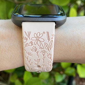 Op de afbeelding: Een lichtroze smartwatchband met een bloemenpatroon. De band is gemaakt van siliconen en heeft een zwart horloge-scherm.