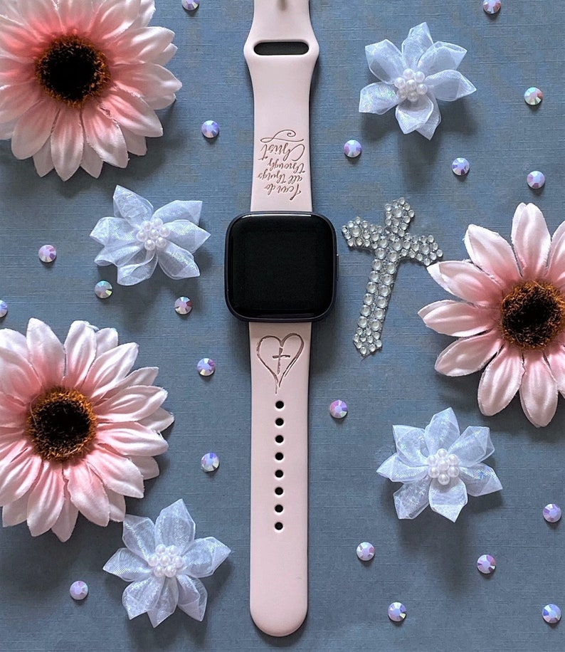 K&ouml;nnte beinhalten: Ein rosafarbenes Silikon-Armband mit einem schwarzen Zifferblatt. Das Armband hat ein Kreuz- und Herzdesign mit dem Text "Love beyond measure, cherish the moments, you're my always".