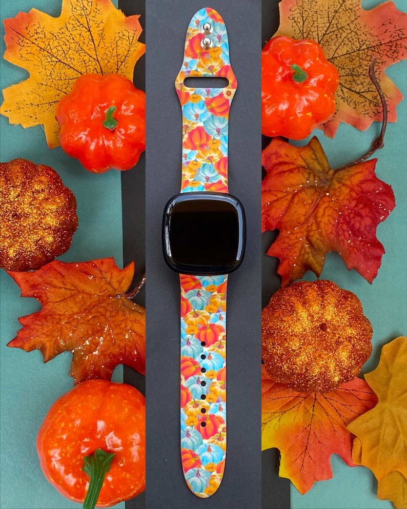 K&ouml;nnte beinhalten: Ein farbenfrohes Armband mit einem K&uuml;rbis- und Herbstlaubmuster. Das Armband ist aus Silikon und kompatibel mit Apple Watch.