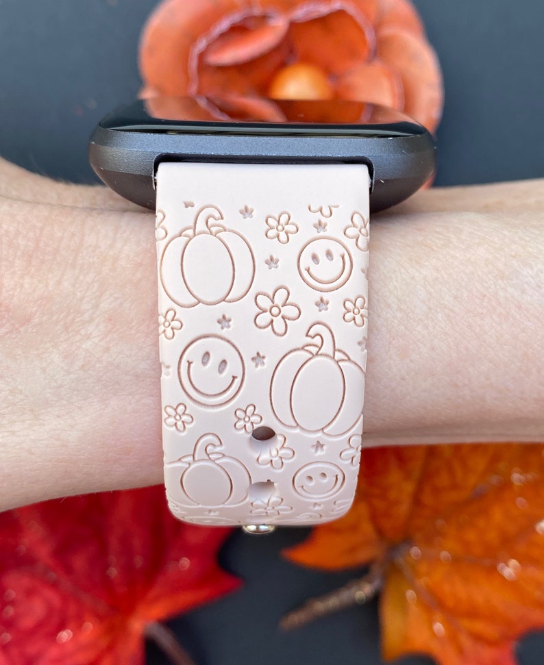 Pu&ograve; includere: Un cinturino per orologio in silicone rosa con un motivo di zucche, faccine sorridenti e fiori. Il cinturino &egrave; progettato per uno smartwatch.