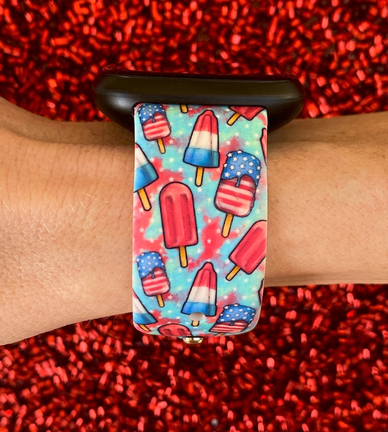 May include: A black Apple Watch band with a blue and white tie-dye pattern and red, white, and blue popsicle graphics.