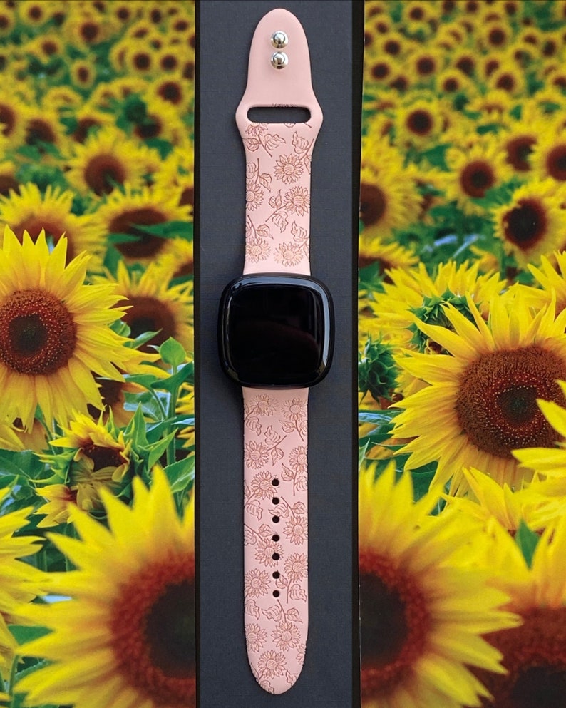 May include: A pink silicone watch band with a sunflower pattern. The band is designed for a smartwatch and has a buckle closure.