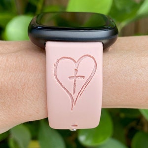 May include: A pink silicone watch band with a heart and cross design.