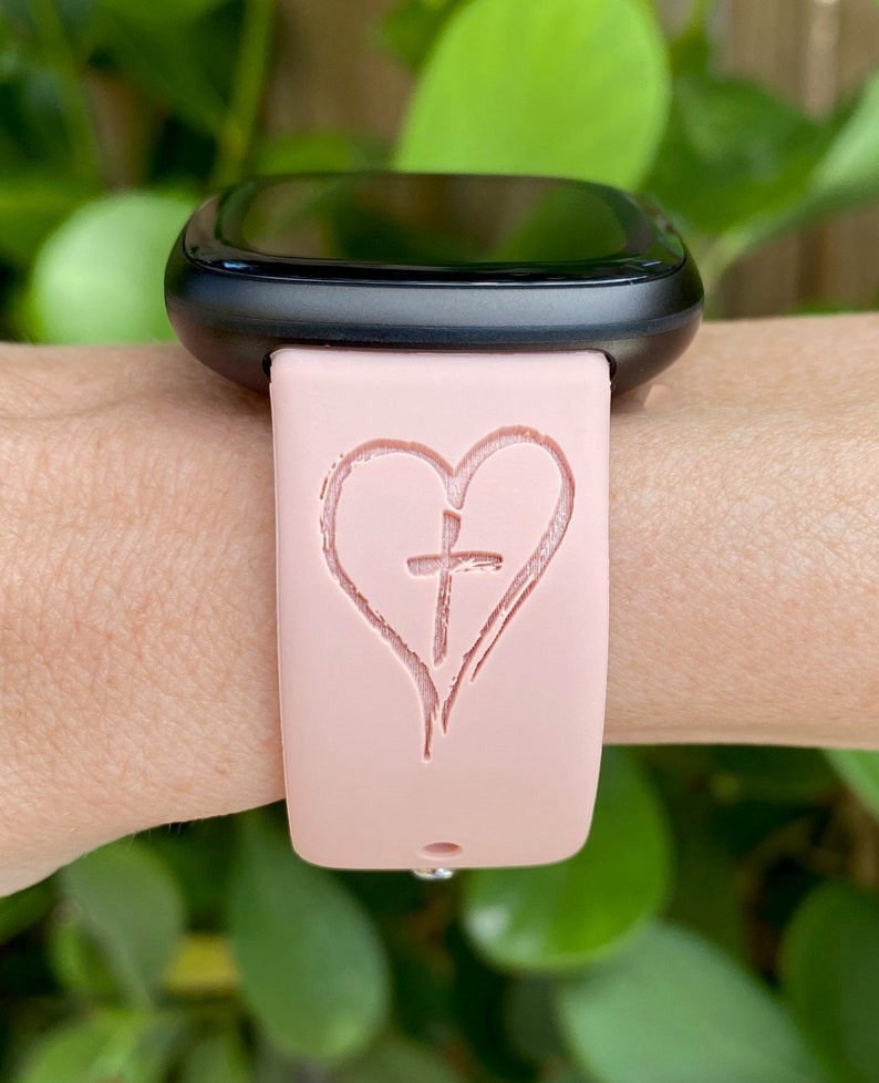 May include: A pink silicone watch band with a heart and cross design.