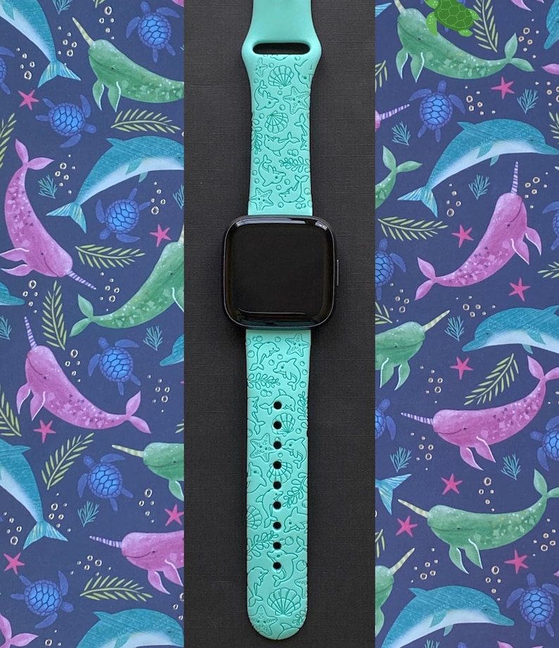 Puede incluir: Una correa de reloj de silicona azul turquesa con un patr&oacute;n de vida marina. La correa presenta un patr&oacute;n repetitivo de narvales, delfines, conchas marinas y estrellas de mar. La correa es compatible con Apple Watch.