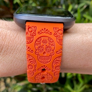 K&ouml;nnte beinhalten: Orangefarbenes Silikon-Armband mit Totenkopf-Motiv.