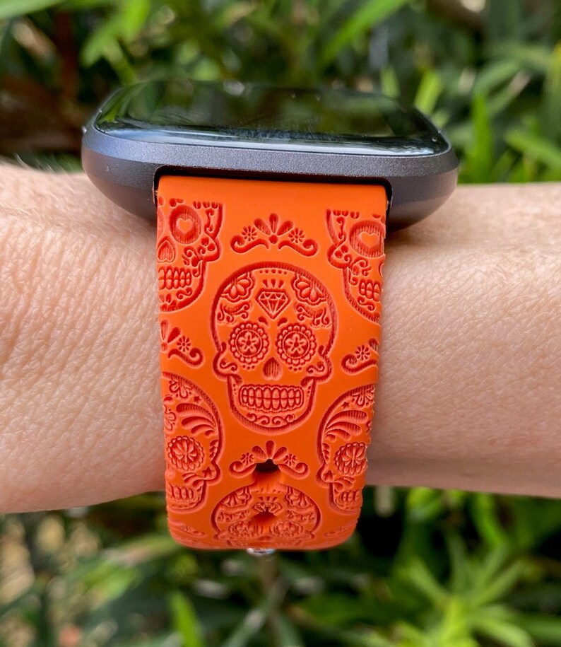 K&ouml;nnte beinhalten: Orangefarbenes Silikon-Armband mit Totenkopf-Motiv.