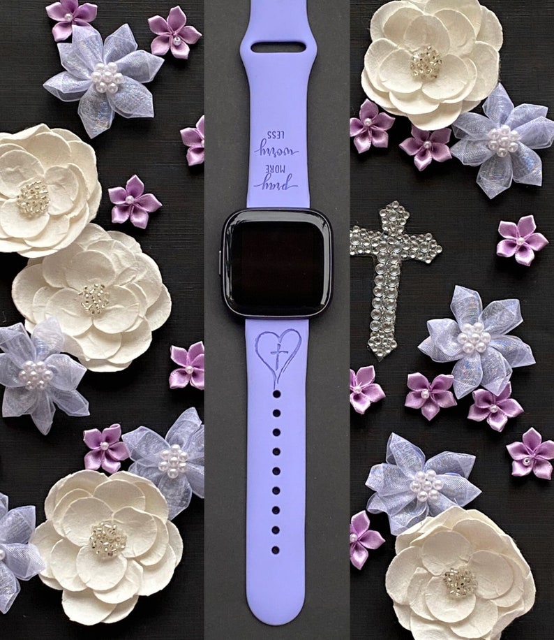May include: A purple silicone watch band with a heart and cross design. The band has the text "more hard less room" engraved on it.