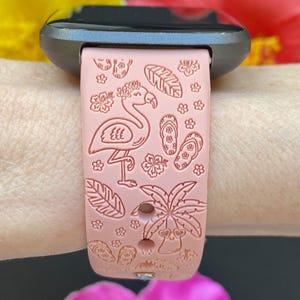 K&ouml;nnte beinhalten: Ein rosafarbenes Silikon-Armband mit einem Flamingo-, Palmen- und Flip-Flop-Design.