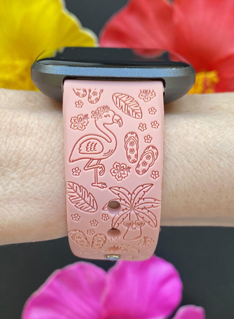 K&ouml;nnte beinhalten: Ein rosafarbenes Silikon-Armband mit einem Flamingo-, Palmen- und Flip-Flop-Design.