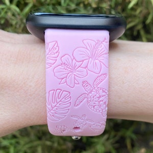 May include: A pink silicone watch strap with a floral and sea turtle design.
