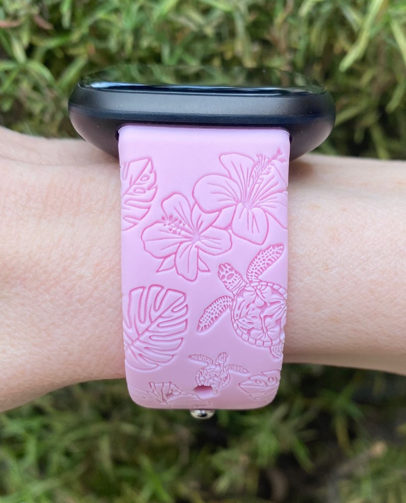 May include: A pink silicone watch strap with a floral and sea turtle design.