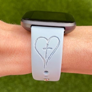 May include: A light blue silicone watch strap with a white heart and cross design.