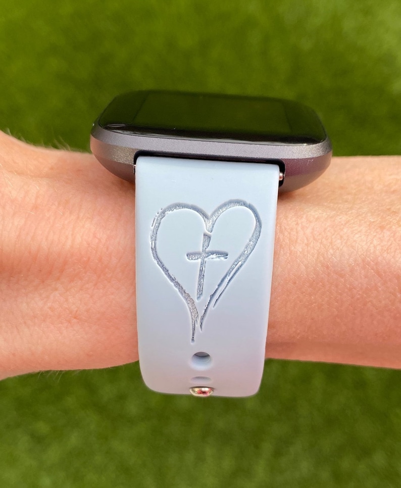 May include: A light blue silicone watch strap with a white heart and cross design.