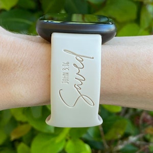 May include: A white silicone watch band with the word "Saved" and the text "JOHN 3:16" engraved on it.