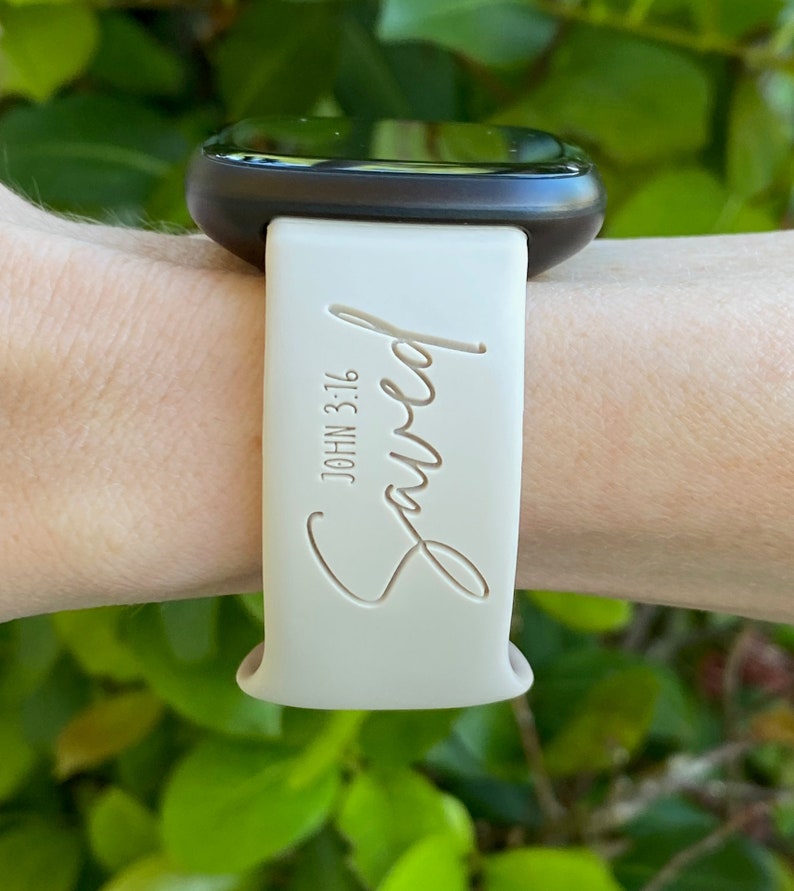 May include: A white silicone watch band with the word "Saved" and the text "JOHN 3:16" engraved on it.