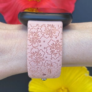 May include: A pink silicone watch band with a floral pattern. The band features a raised design of hibiscus flowers and stars.