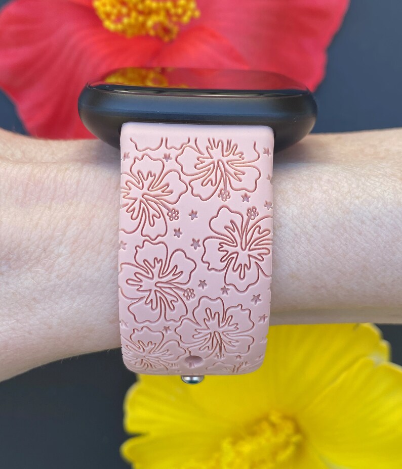 May include: A pink silicone watch band with a floral pattern. The band features a raised design of hibiscus flowers and stars.