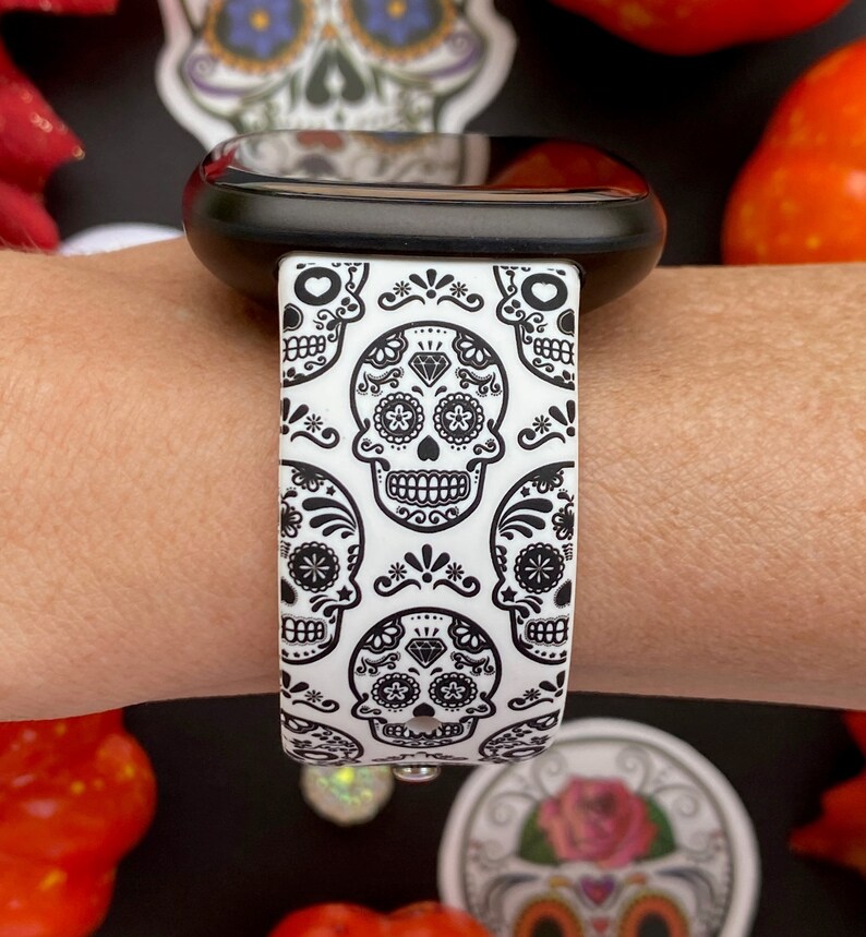 May include: White and black watch band with a repeating pattern of sugar skulls. The band is made of silicone and has a smooth finish.