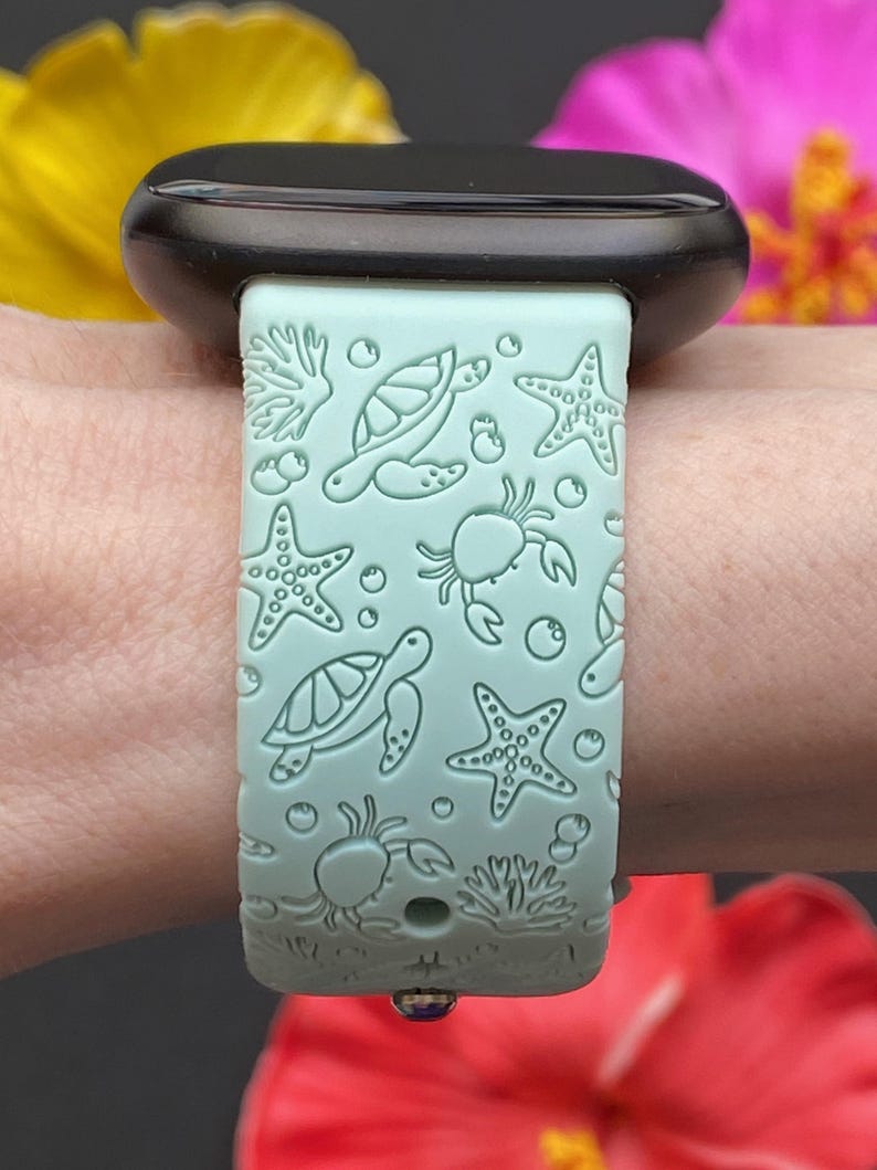 May include: A light blue silicone watch band with a sea life design. The band features sea turtles, starfish, crabs, and coral.