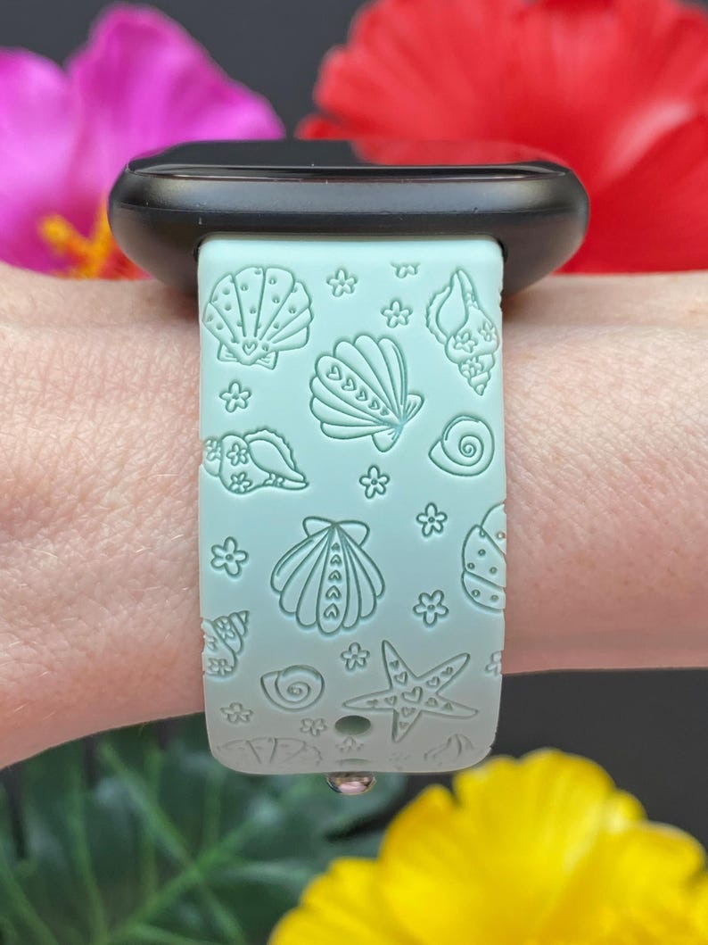 May include: A light blue silicone watch band with a seashell and starfish pattern. The band is designed for a smartwatch.