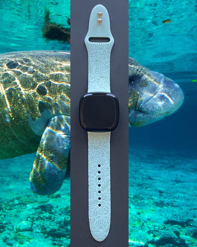May include: A light blue smartwatch band with a black screen. The band features a repeating pattern of sea creatures and shells. The background shows a manatee swimming in clear blue water.