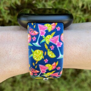 May include: A black smartwatch with a blue and pink silicone band featuring a pattern of cocktails and lemons.