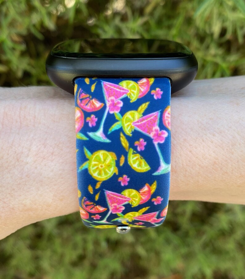 May include: A black smartwatch with a blue and pink silicone band featuring a pattern of cocktails and lemons.