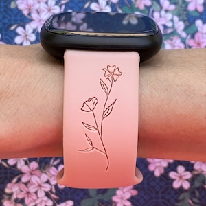 May include: A pink silicone watch band with a delicate floral design. The band is compatible with smartwatches.