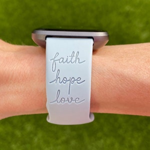 May include: A light blue silicone watch strap with the words "faith hope love" engraved on it.