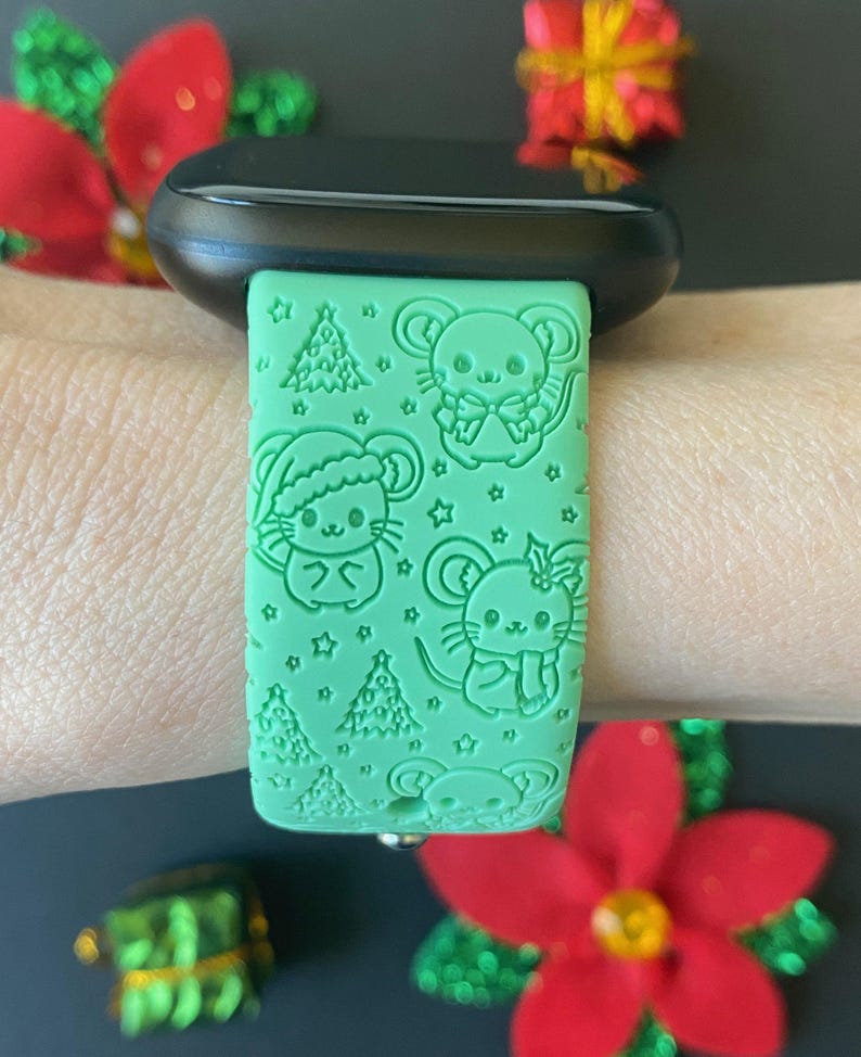May include: A green silicone watch band with a Christmas theme. The band features a repeating pattern of mice wearing Santa hats, Christmas trees, and stars.
