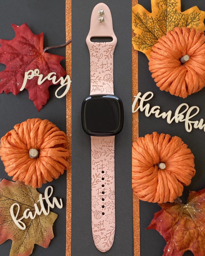 May include: A pink smartwatch band with a black watch face, featuring a repeating pattern of leaves, pumpkins, and text. The words "Created with a Purpose", "Grow in Faith", and "Jesus" are visible. The image includes decorative pumpkins and leaves.