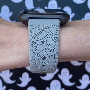 Puede incluir: Una correa de reloj de silicona gris con un patr&oacute;n de fantasmas blancos y flores. La correa est&aacute; dise&ntilde;ada para un reloj inteligente con una cara cuadrada.