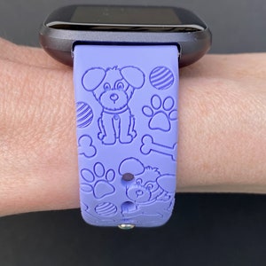 May include: A purple silicone watch band with a dog bone, paw print, and dog silhouette design.