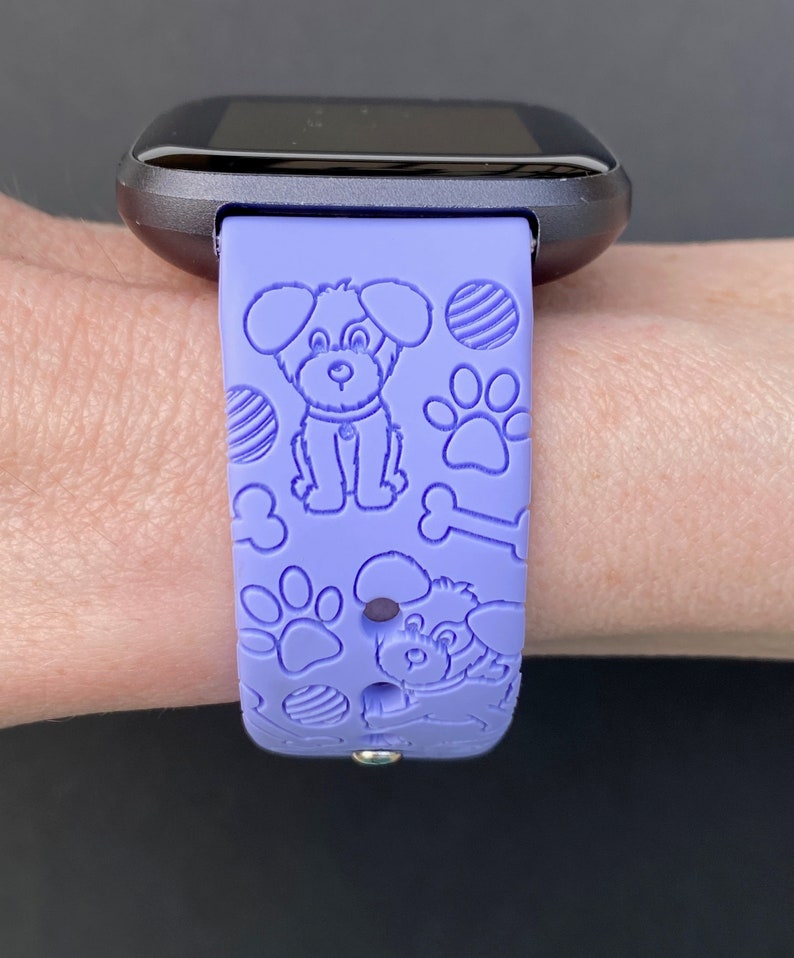 May include: A purple silicone watch band with a dog bone, paw print, and dog silhouette design.