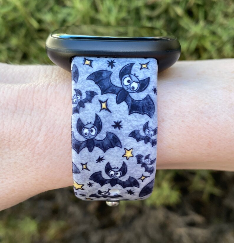 Puede incluir: Una correa de reloj gris y negra con un patr&oacute;n de murci&eacute;lagos y estrellas. La correa est&aacute; hecha de un material suave y flexible y es compatible con la mayor&iacute;a de los relojes inteligentes.