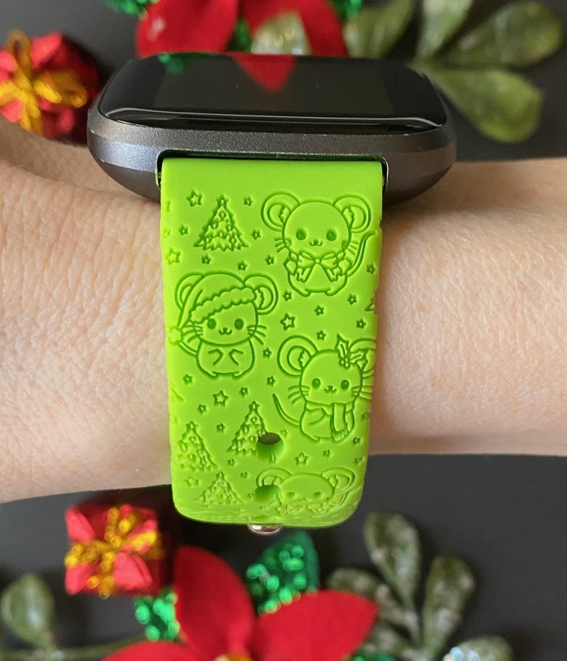 May include: A green smartwatch band with a Christmas-themed design featuring cartoon mice and Christmas trees.