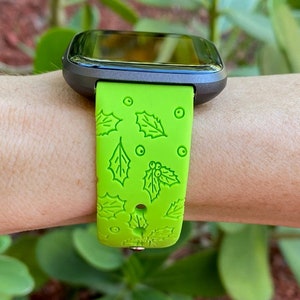 Puede incluir: Una correa de reloj de silicona verde con un patr&oacute;n de acebo y bayas. La correa est&aacute; dise&ntilde;ada para un reloj inteligente.
