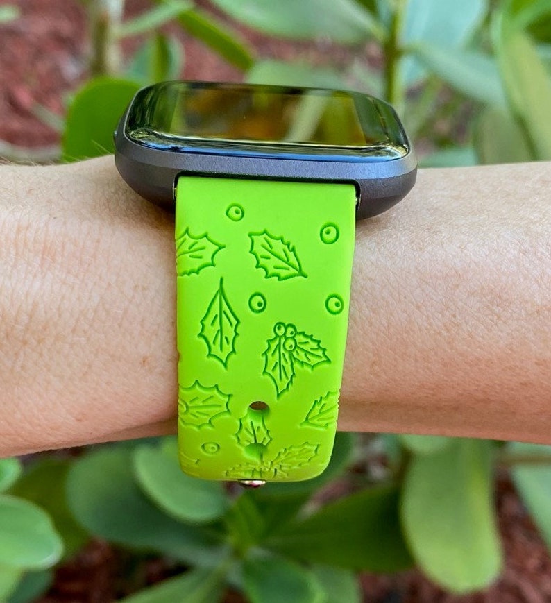 Puede incluir: Una correa de reloj de silicona verde con un patr&oacute;n de acebo y bayas. La correa est&aacute; dise&ntilde;ada para un reloj inteligente.