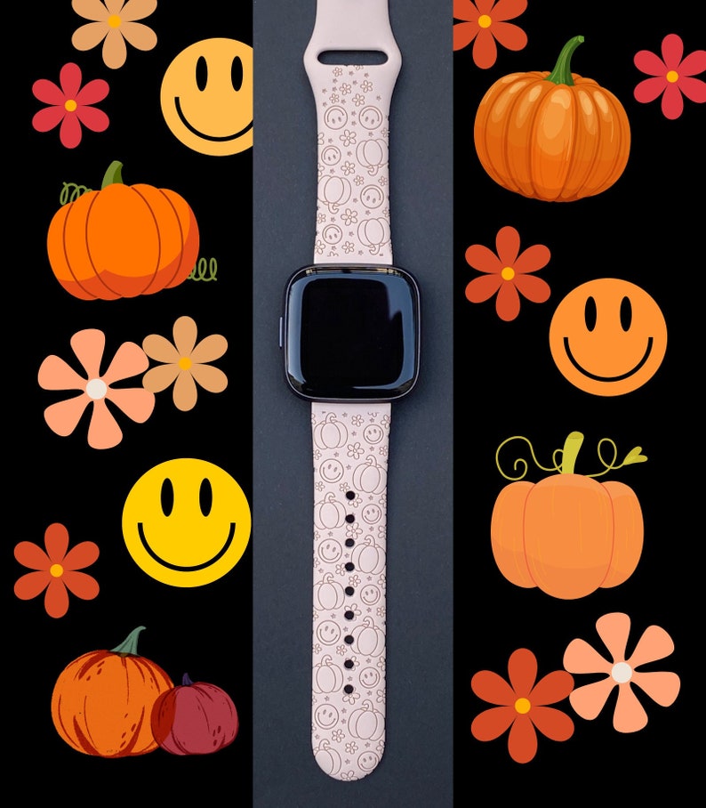 Pu&ograve; includere: Un cinturino rosa per smartwatch con sfondo bianco e un motivo di facce sorridenti e zucche. Il cinturino &egrave; su uno sfondo nero.