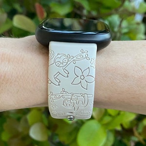 May include: A white smartwatch band with a black watch face. The band has a pattern of sloths and flowers.
