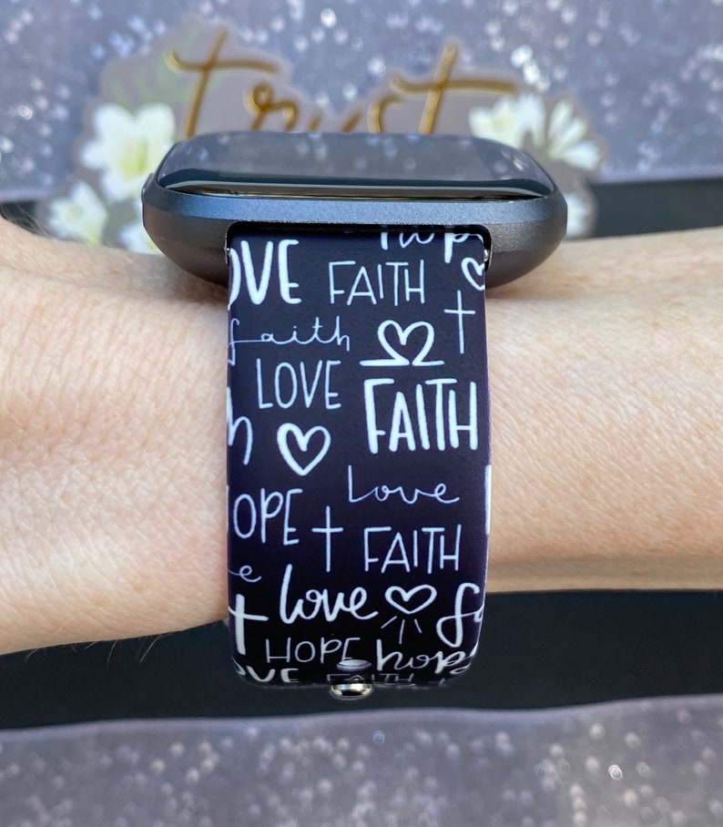 K&ouml;nnte beinhalten: Schwarz-wei&szlig; gemustertes Armband mit den Worten "Love", "Faith" und "Hope", die in handschriftlicher Form wiederholt werden.