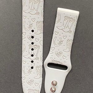 May include: White silicone watch band with a pattern of cowboy boots, horseshoes, and hearts. The band is designed for a smartwatch.