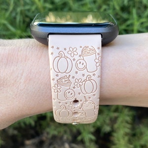 May include: A light pink silicone watch band with a fall-themed design. The band features pumpkins, coffee cups, and stars.