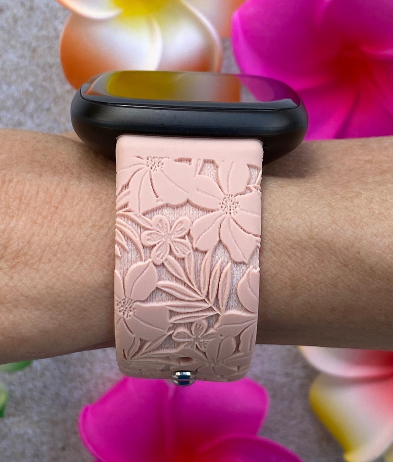 Puede incluir: Una correa de reloj de silicona rosa con un dise&ntilde;o floral. La correa est&aacute; estampada con un patr&oacute;n de flores y hojas.