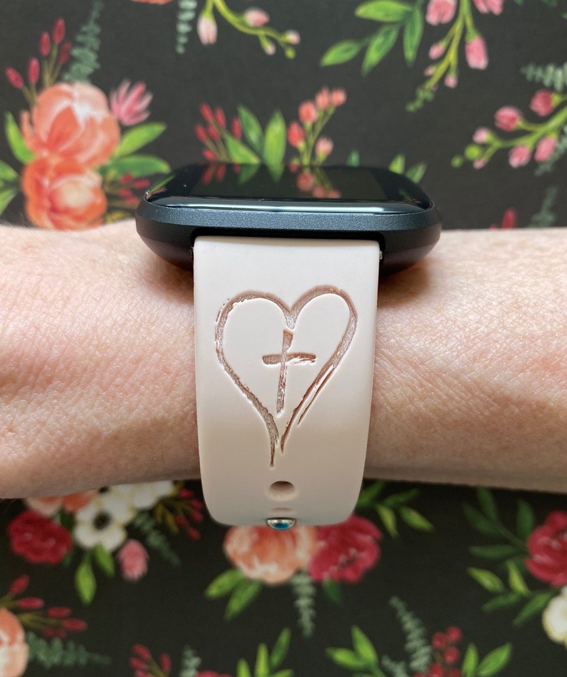 K&ouml;nnte beinhalten: Ein rosafarbenes Silikon-Armband mit einem Herz- und Kreuzdesign.