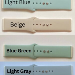 May include: Four silicone watch bands in different colors: light blue, beige, blue green, and light gray. Each band has a white edge and silver metal accents.