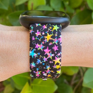 May include: A black fitness tracker with a colorful star pattern band. The band has pink, yellow, blue, and green stars on a black background.