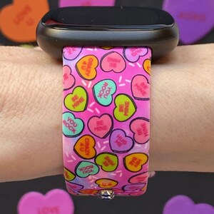May include: Pink and white watch band with a pattern of candy hearts that say "Be Mine", "You Rock", "Hug Me", and "Crazy 4 U".
